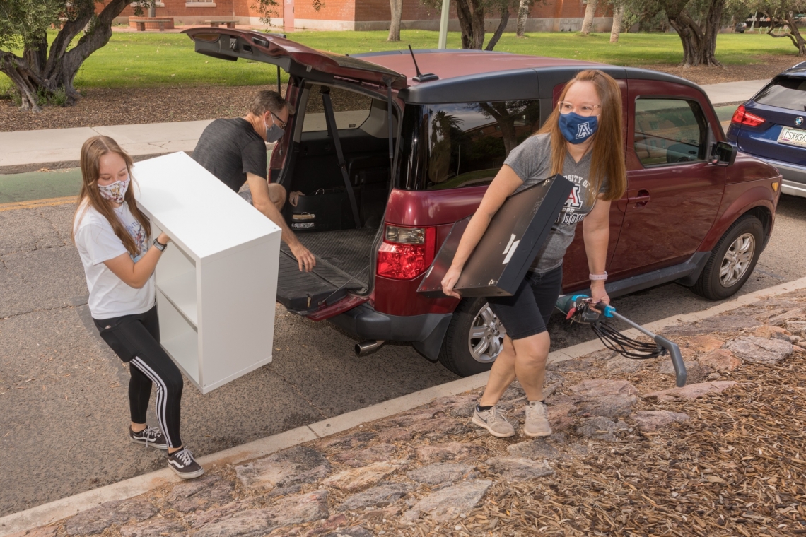 masked people moving furniture into a dorm