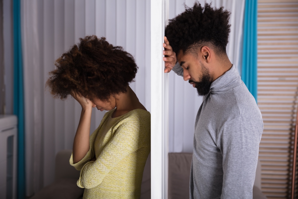 two members of a couple with their heads in their hands