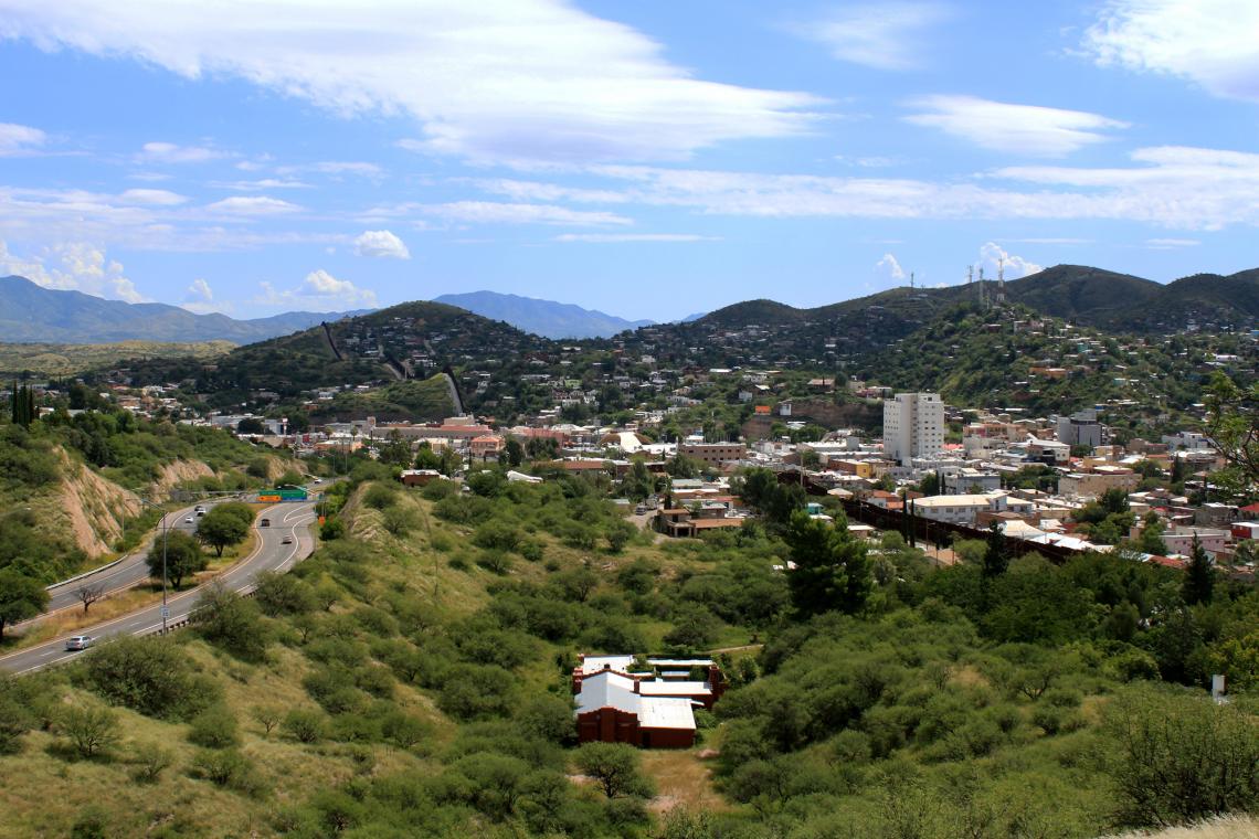 At the southernmost part of the Canamex Corridor sits the border community of Ambos Nogales in Arizona and Sonora, Mexico. A rust-colored steel barrier divides the two cities. At the southernmost part of the Canamex Corridor sits the border community of Ambos Nogales in Arizona and Sonora, Mexico. A rust-colored steel barrier divides the two cities.