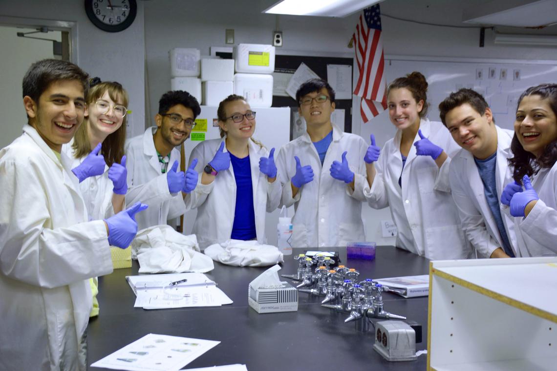 high school students doing thumbs up while in a laboratory gathered around a table 2018 KEYS interns pose with their successful protein gel during biotechnology training.