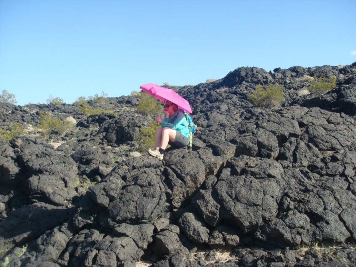 A University of Arizona Lunar and Planetary Laboratory student holds a bright umbrella over the spot where she found geologic contact between two different lava flows during a trip to Amboy Crater in California's Mojave Desert. A University of Arizona Lunar and Planetary Laboratory student holds a bright umbrella over the spot where she found geologic contact between two different lava flows during a trip to Amboy Crater in California's Mojave Desert.
