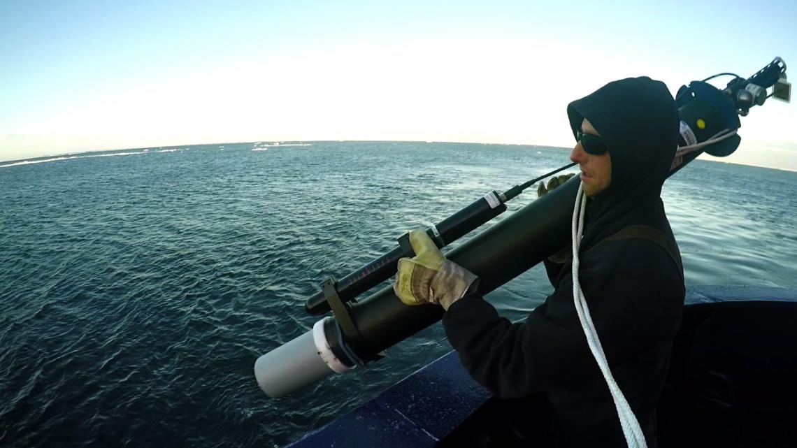 A researcher prepares to deploy a robotic float into the Southern Ocean, the water body surrounding Antarctica. The floats are lowered over the side of the vessel on a rope and slide off the rope once in the water. 