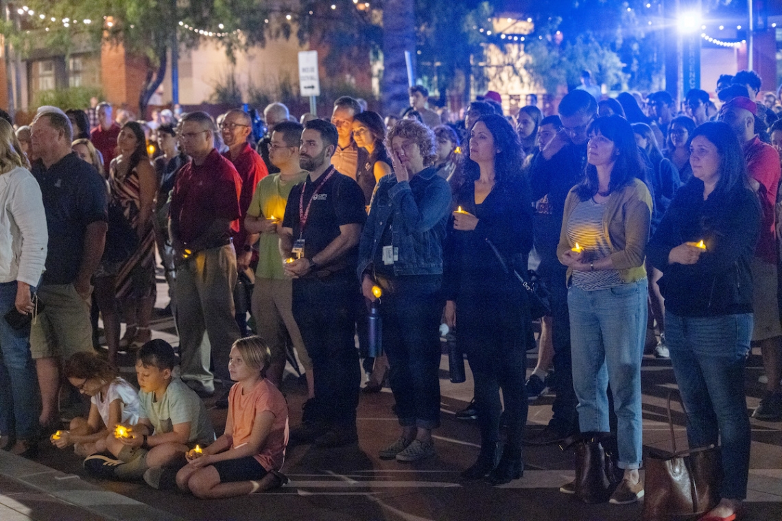 children sitting on curb with adults standing behind them