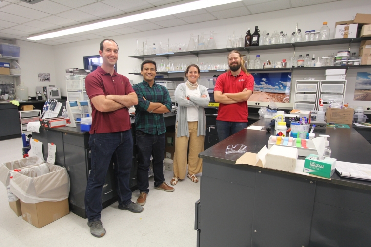 four people standing next to each other in a lab