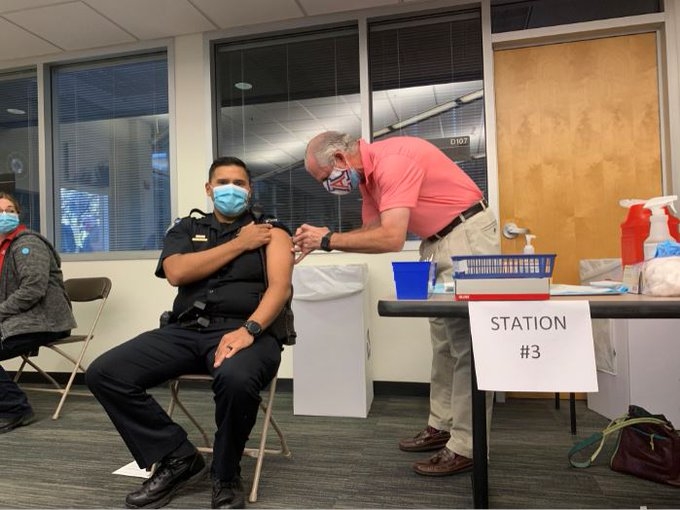 President Robert C. Robbins vaccinates a police officer