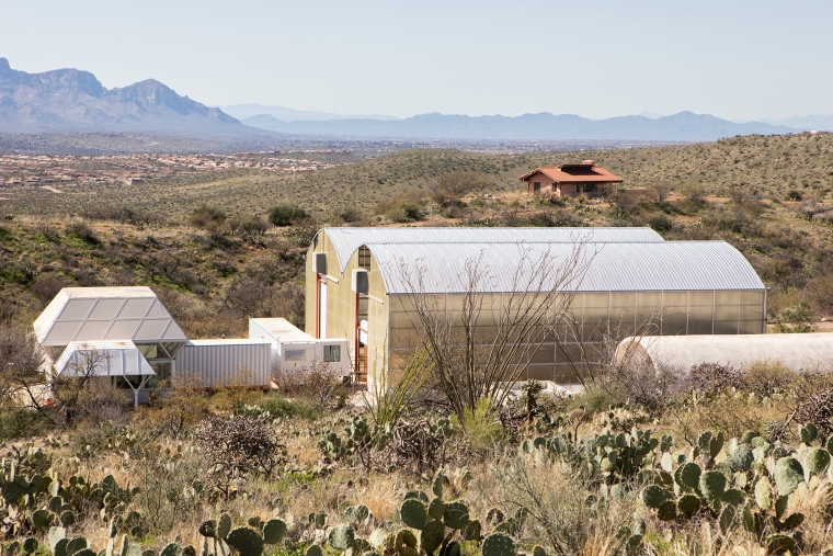 a group of industrial-looking buildings in the middle of a desert landscape