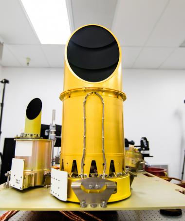 The OSIRIS-REx mission's suite of three cameras, collectively known as OCAMS, sits on a test bench that mimics its arrangement on the spacecraft. The OSIRIS-REx mission's suite of three cameras, collectively known as OCAMS, sits on a test bench that mimics its arrangement on the spacecraft.